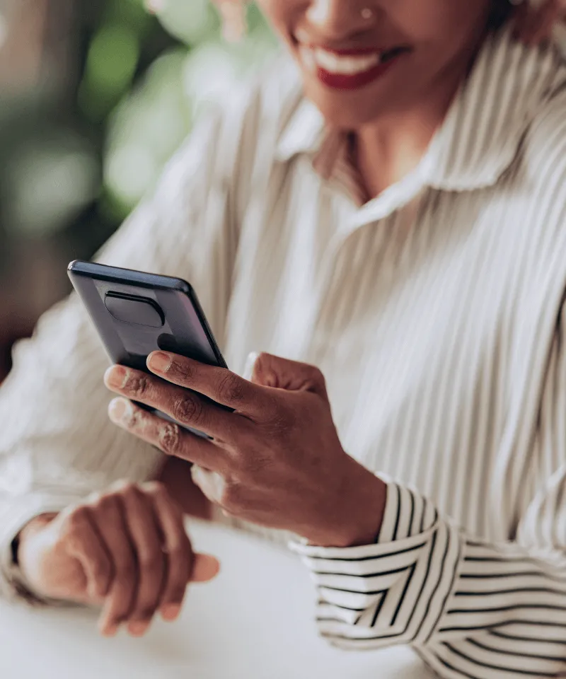 Une cliente souriant tout en tenant son téléphone portable