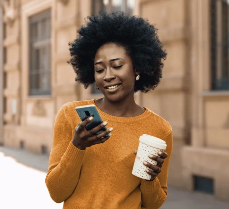 A woman checking her phone while on a coffee run