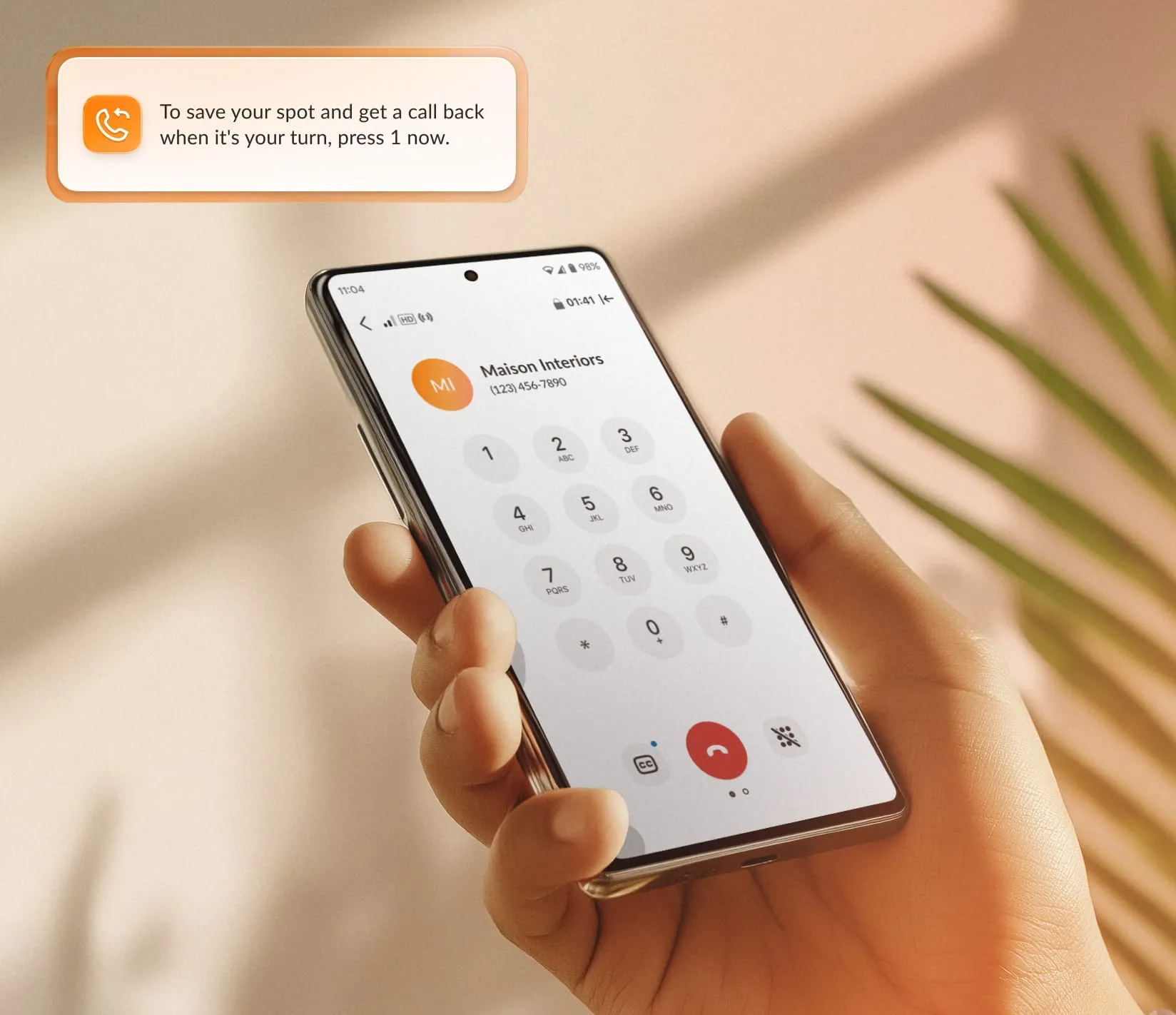 A person holds a smartphone displaying the RingCentral App's call interface. The screen shows a dial pad and the contact information of the caller.