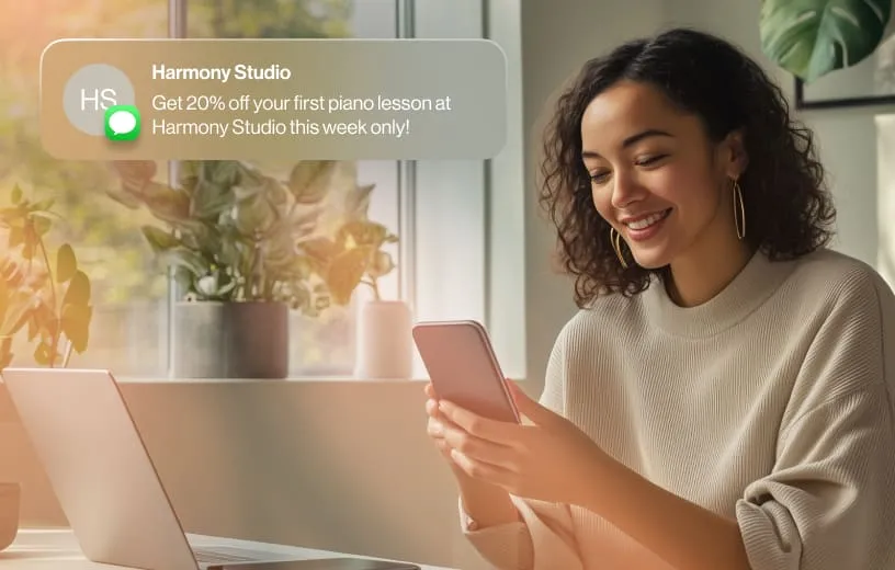 A woman gets holding her mobile phone in front of her laptop receives a promotional SMS from Harmony Studio