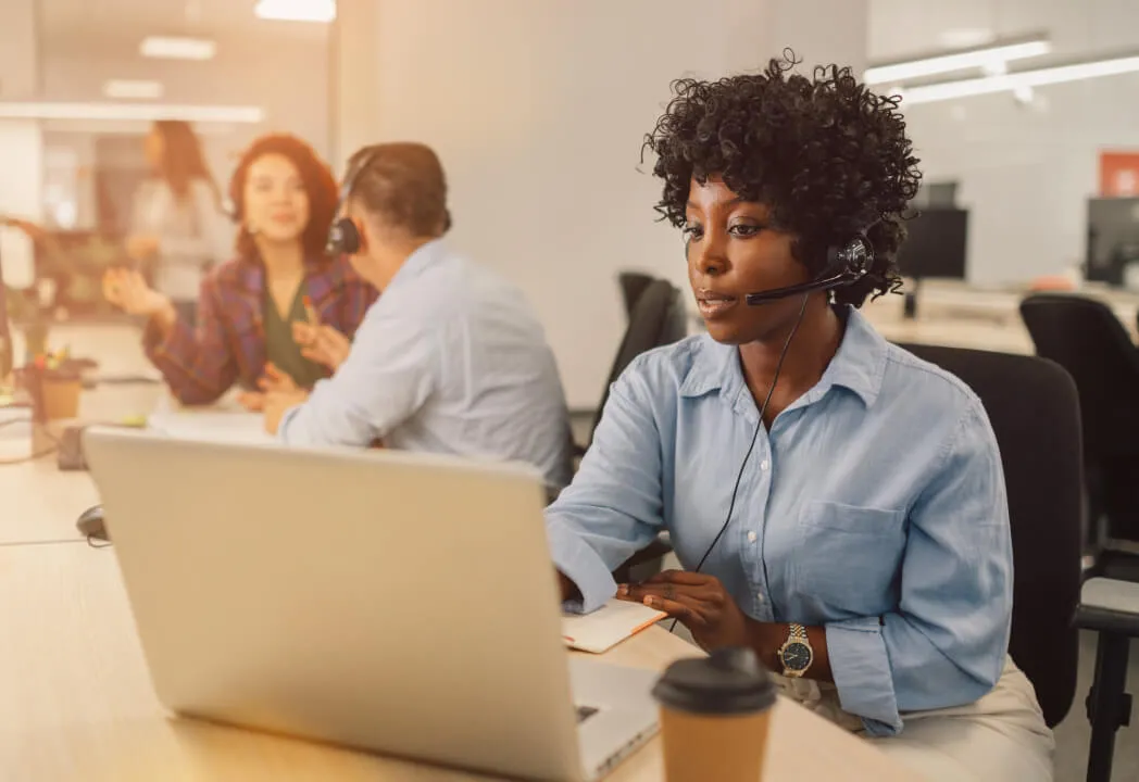 A customer service agent at a call center speaking on a headset