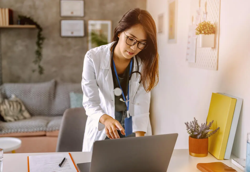 Young female doctor examines a patient's chart on her laptop