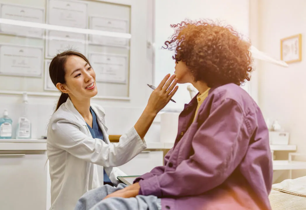Dermatologist in a white coat examines the skin of a young curly-haired patient
