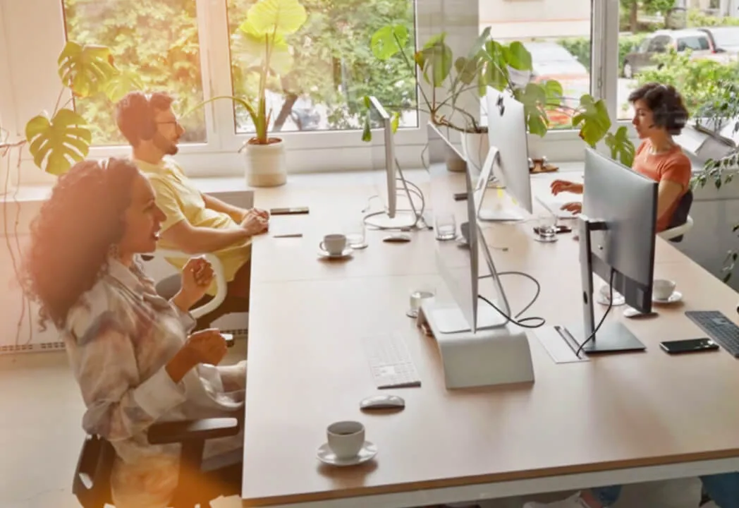 Four customer support employees working in an open office space